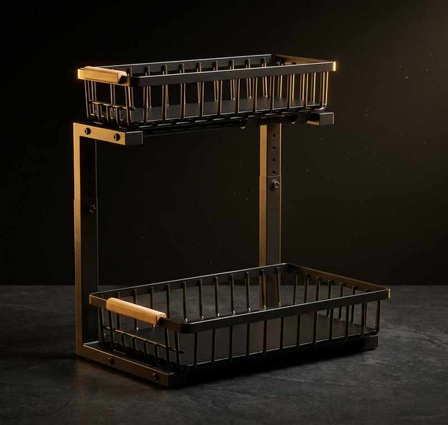 A two-tier wire basket shelf with a black metal body and warm brass-toned frame, featuring light wood handles on the upper basket rim and a lower basket handle, shown against a dark studio background.