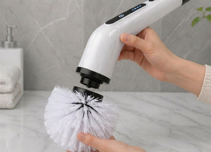 Handheld cleaning tool with interchangeable brush head held by a person in a bathroom setting.