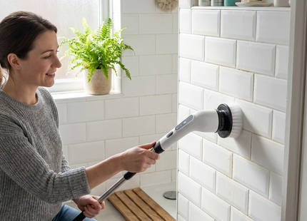 Woman using the WSGenie Cordless Electric Spin Scrubber to clean shower tiles in a UK home bathroom