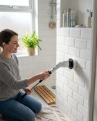 Woman using the WSGenie Cordless Electric Spin Scrubber to clean shower tiles in a UK home bathroom
