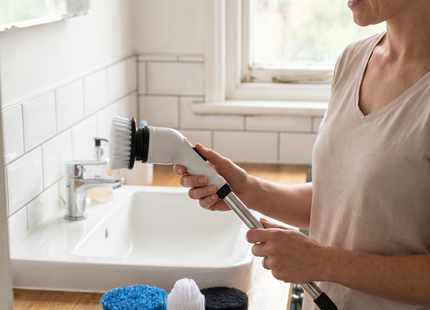 Woman in a bathroom with the WSGenie Complete Clean Kit, spin scrubber and brush heads