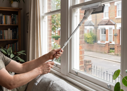 Person cleaning a window with the WSGenie 2-in-1 window squeegee with spray head
