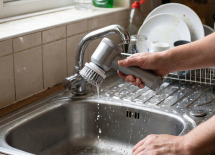 Person scrubbing a kitchen sink with the WSGenie multifunctional electric cleaning brush
